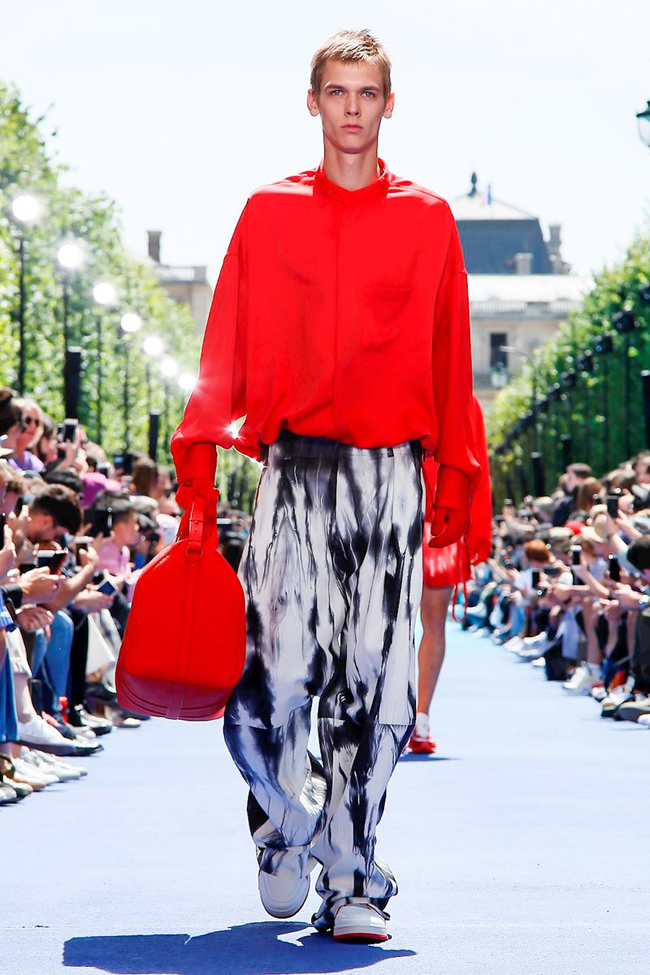 Louis Vuitton Paris Menswear S S Bare foot male model wearing crinkled pink  shirt and peach shorts, carrying red holdall Stock Photo - Alamy