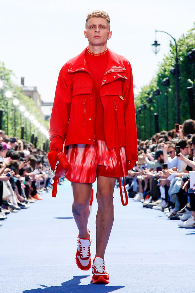 Louis Vuitton Paris Menswear S S Bare foot male model wearing crinkled pink  shirt and peach shorts, carrying red holdall Stock Photo - Alamy