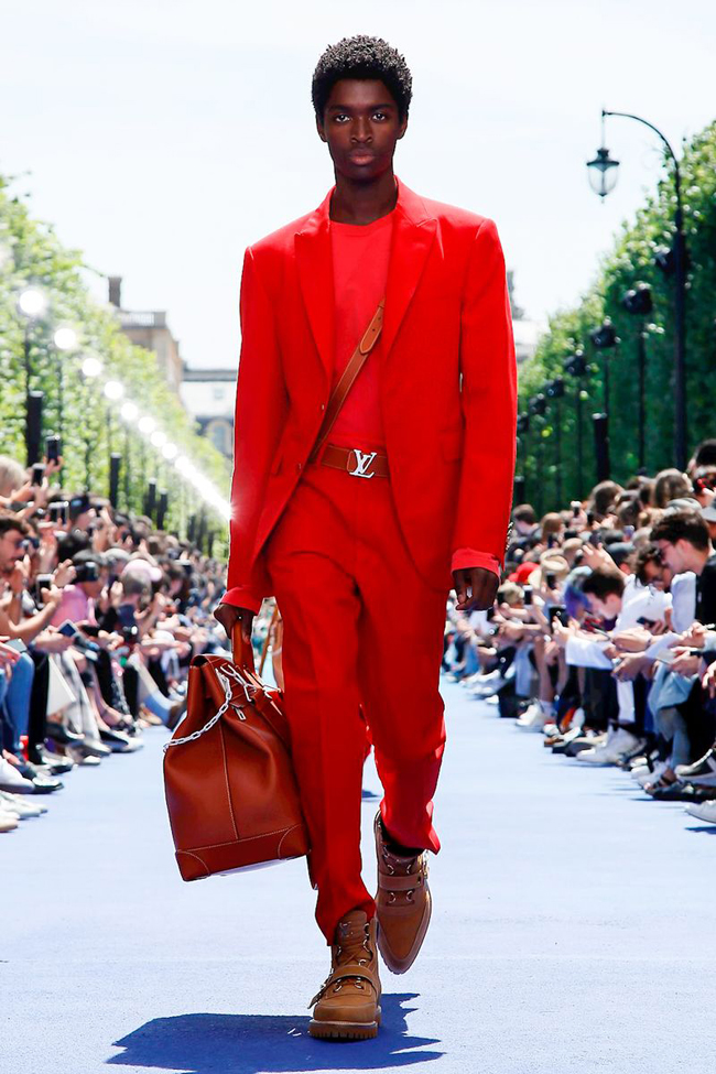 Louis Vuitton Paris Menswear S S Bare foot male model wearing crinkled pink  shirt and peach shorts, carrying red holdall Stock Photo - Alamy