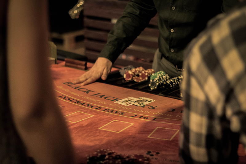 Woman croupier near card table in casino offers to play black jack