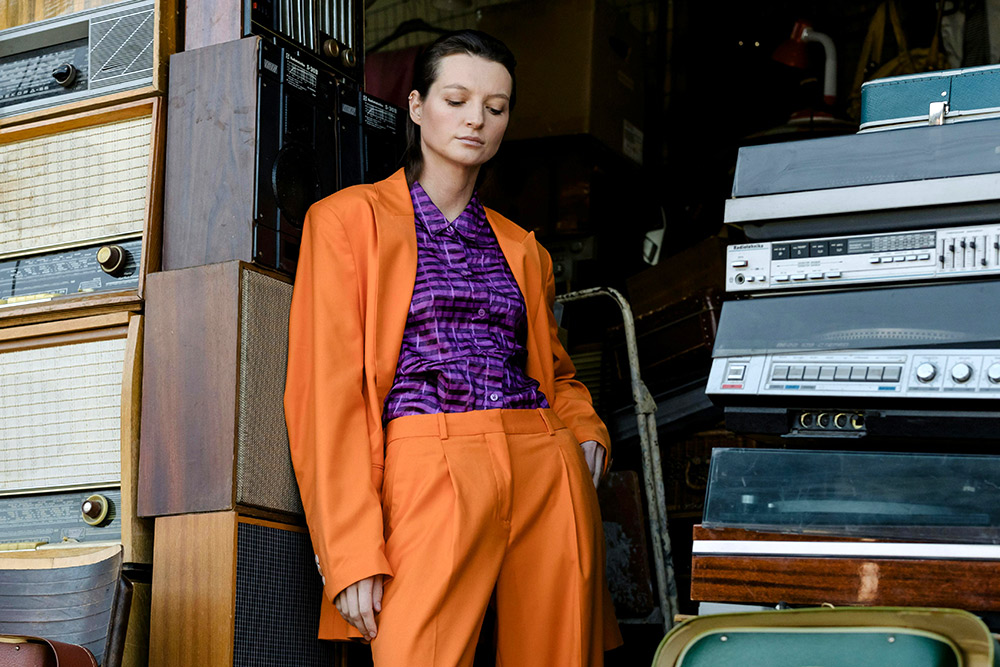 Modern take on a bold orange power suit, inspired by fashion eras that left a permanent mark, like the 1980s.