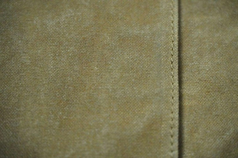A close view of a stitched seam running through plain tan fabric