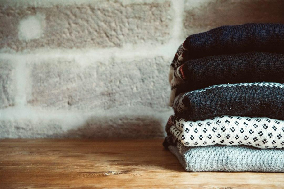 A stack of folded wool sweaters on a wooden table